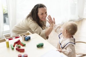 ABA Therapist from Soaring High giving high fives to a baby